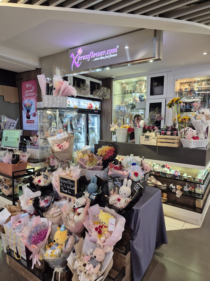 An interior view of Xpressflower, showcasing various floral arrangements, preserved flowers, and plush toy bouquets.