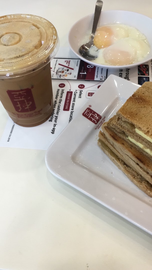 A classic Ya Kun Kaya Toast breakfast set featuring kaya toast, soft-boiled eggs, and iced coffee.