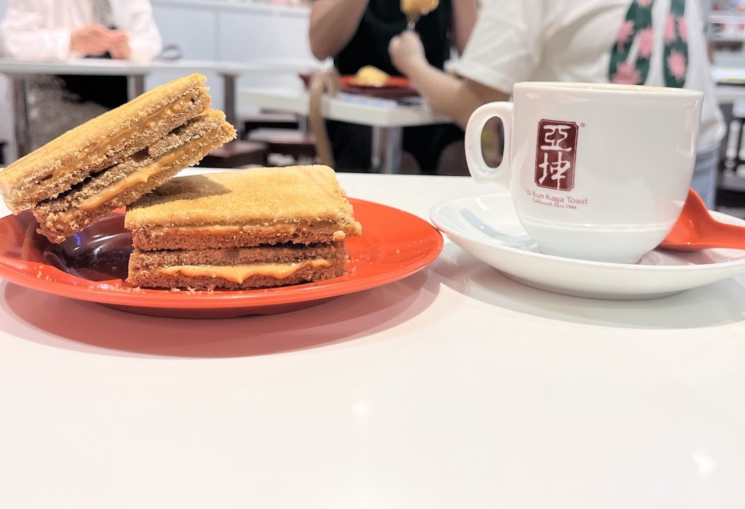 A close-up of traditional kaya toast and a cup of coffee on a white table at Ya Kun Kaya Toast.