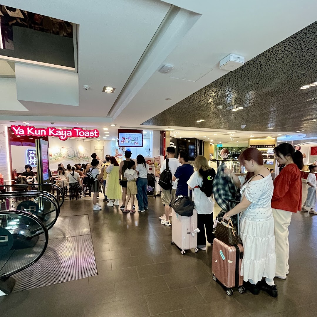 Customers queueing outside Ya Kun Kaya Toast, a popular traditional breakfast spot, within a bustling mall.