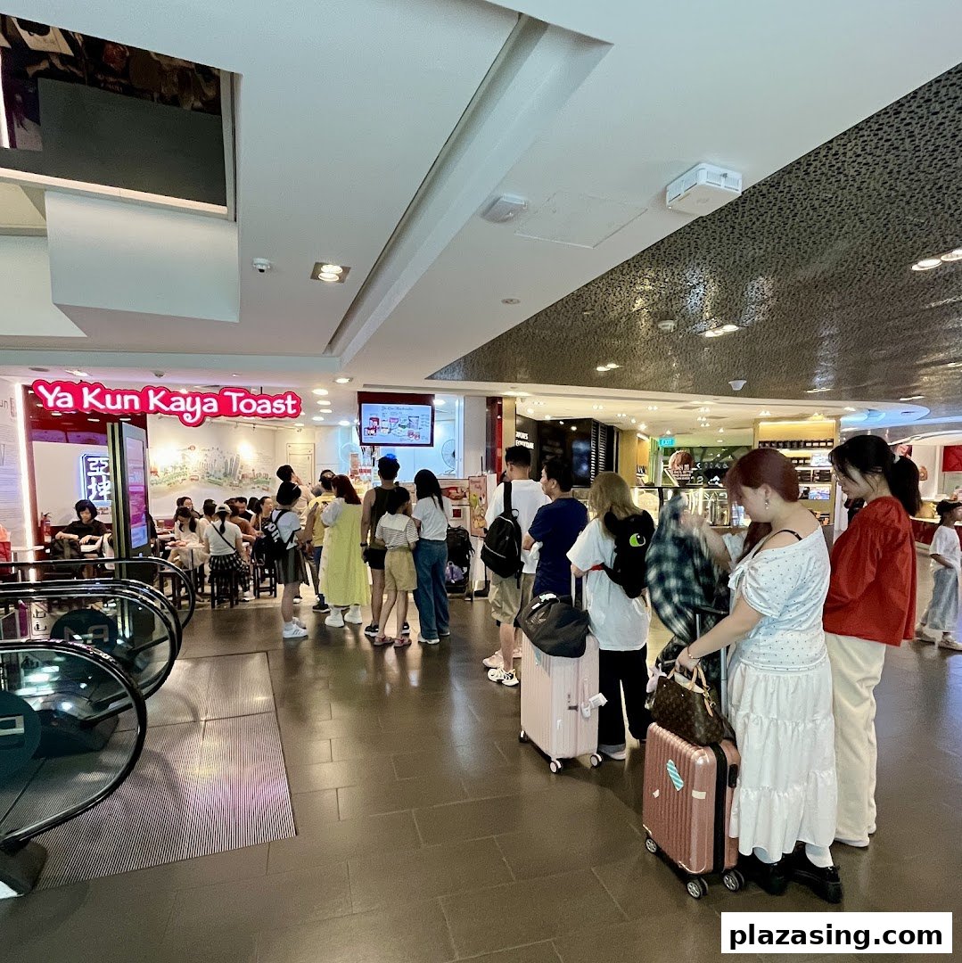 Customers queueing outside Ya Kun Kaya Toast, a popular traditional breakfast spot, within a bustling mall.