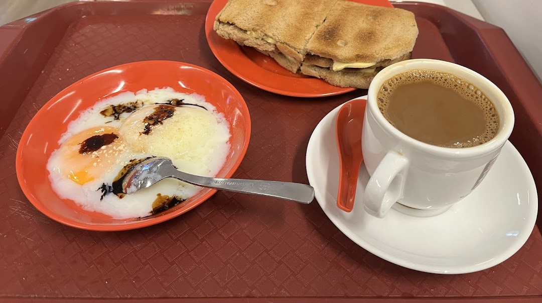A classic Singaporean breakfast set featuring soft-boiled eggs, kaya toast, and a cup of coffee.