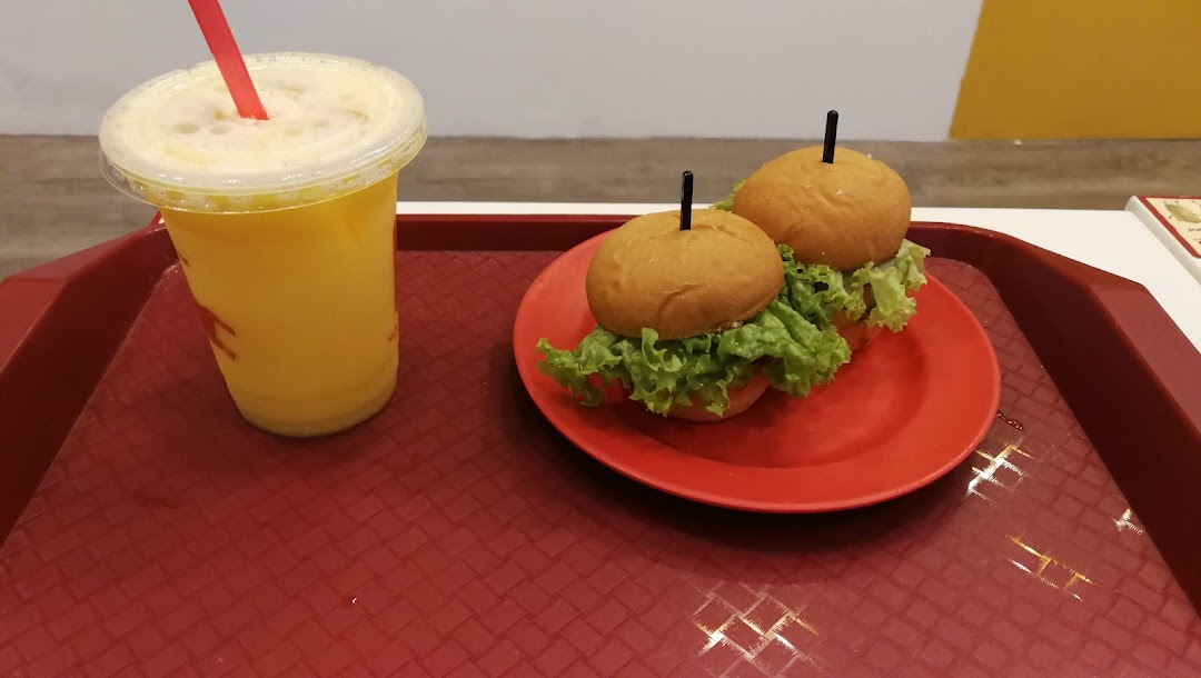 A vibrant yellow drink and two mini burgers with lettuce on a red tray.