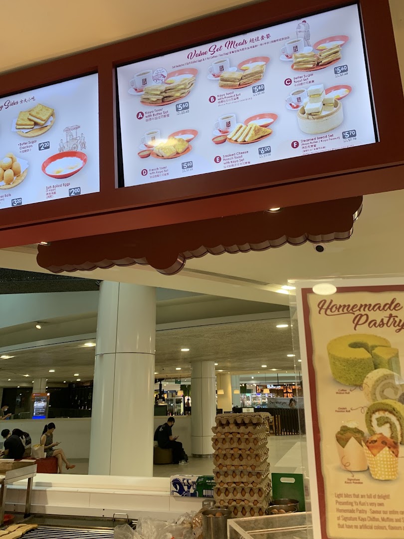 A brightly lit menu board at Ya Kun Kaya Toast displaying various value set meals and side dishes.