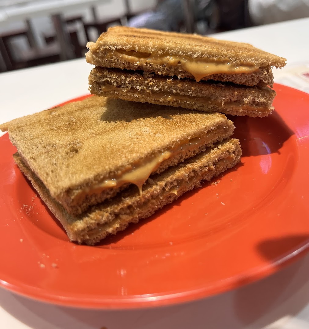 Two stacks of toasted bread with creamy peanut butter filling are served on a vibrant red plate.