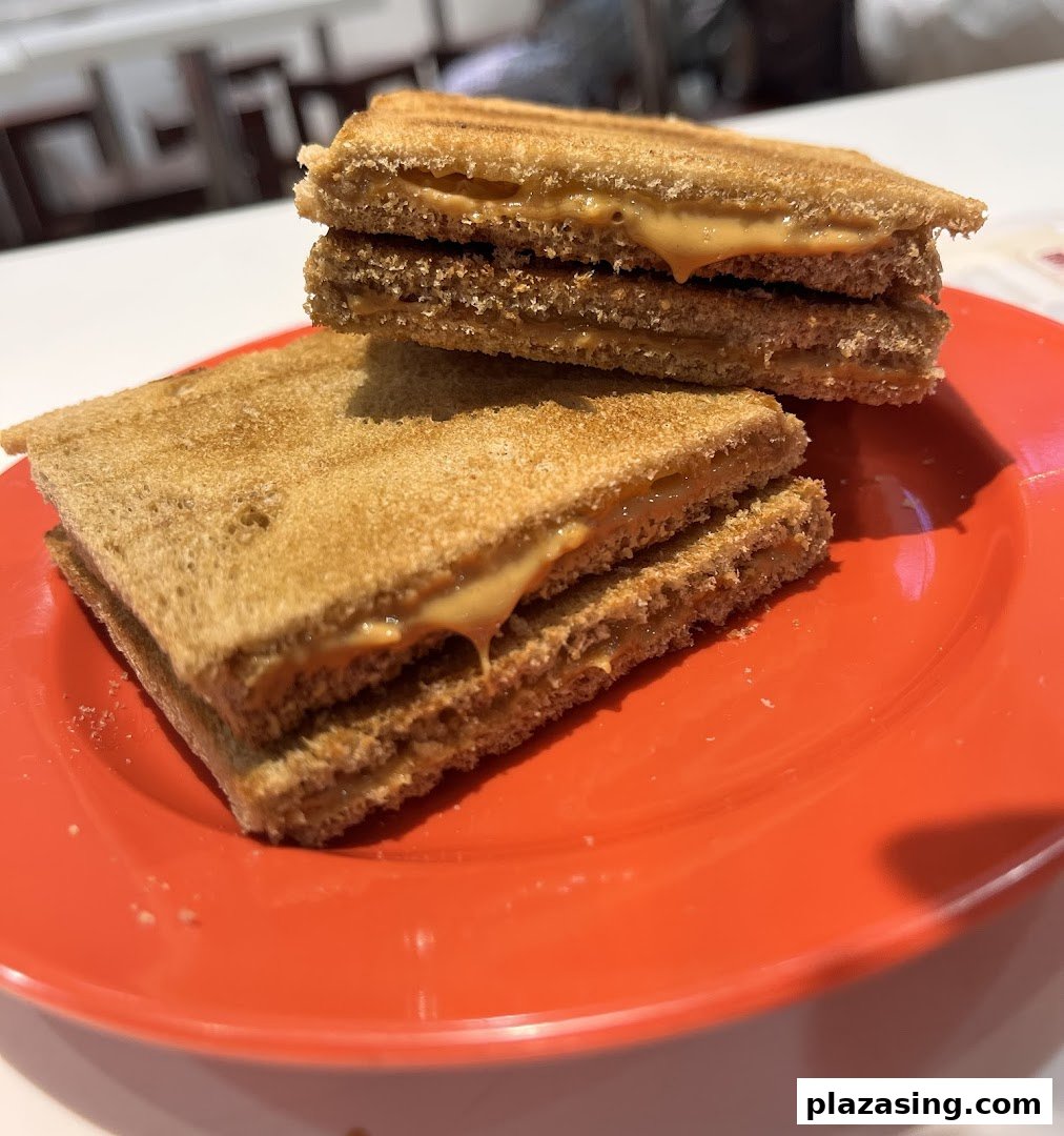 Two stacks of toasted bread with creamy peanut butter filling are served on a vibrant red plate.