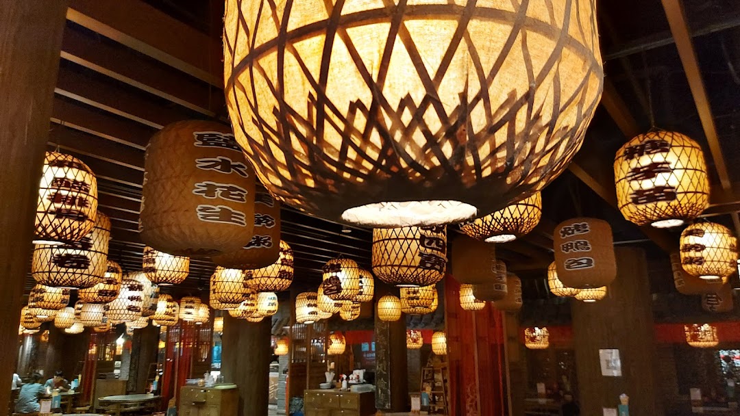 A warm interior view of a restaurant, featuring numerous illuminated traditional lanterns hanging from the ceiling.
