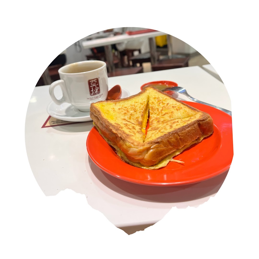 A plate of golden French toast and a cup of coffee on a white table at Ya Kun Kaya Toast.