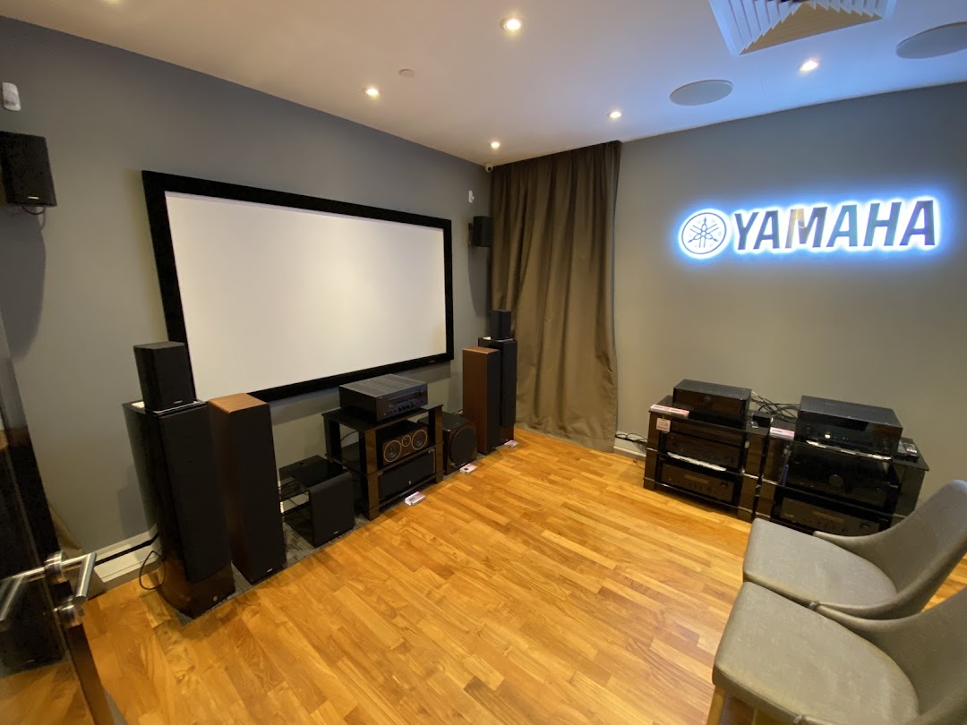 An immersive home theater demo room featuring Yamaha audio-visual equipment and a large projection screen.