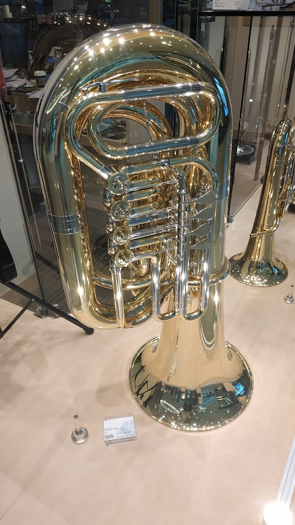 A large, shiny brass tuba is prominently displayed in a music store.