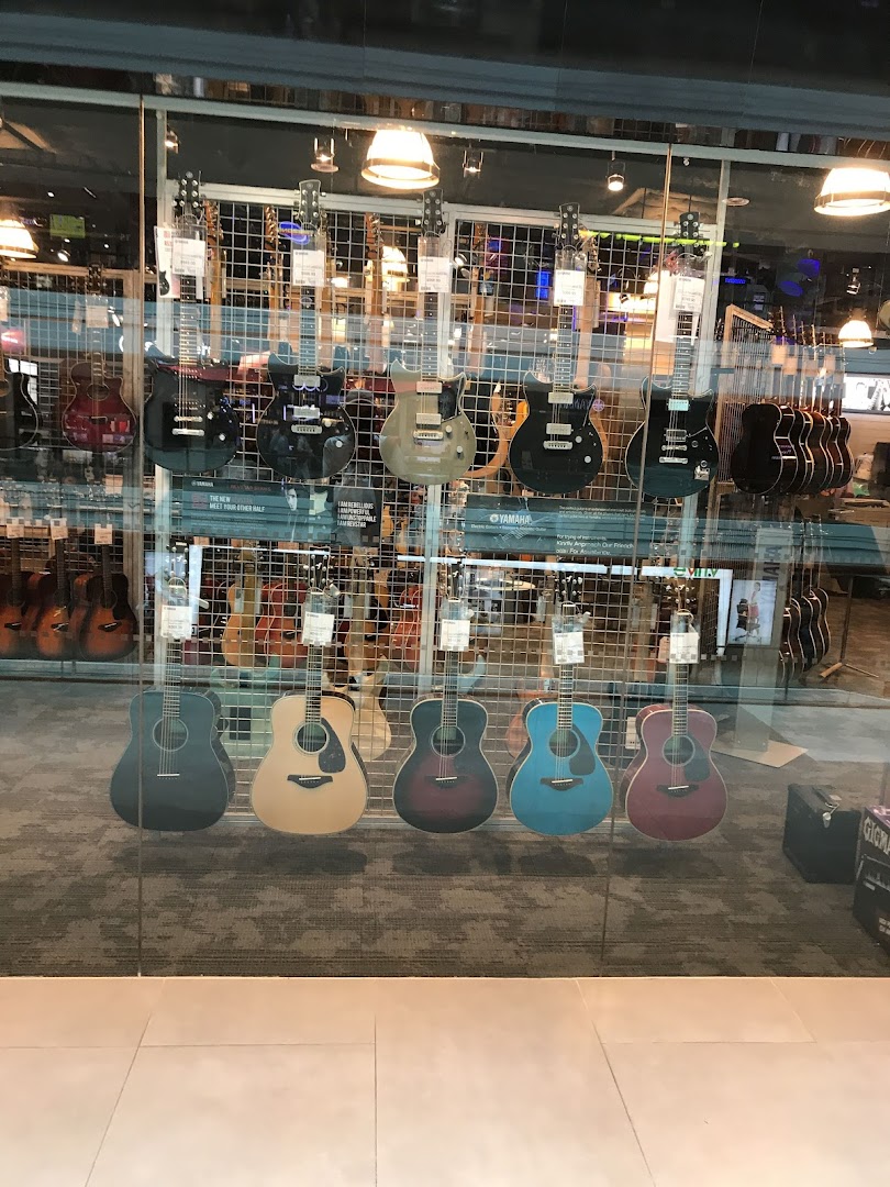 A vibrant display of acoustic and electric guitars showcased through the glass front of a music store.