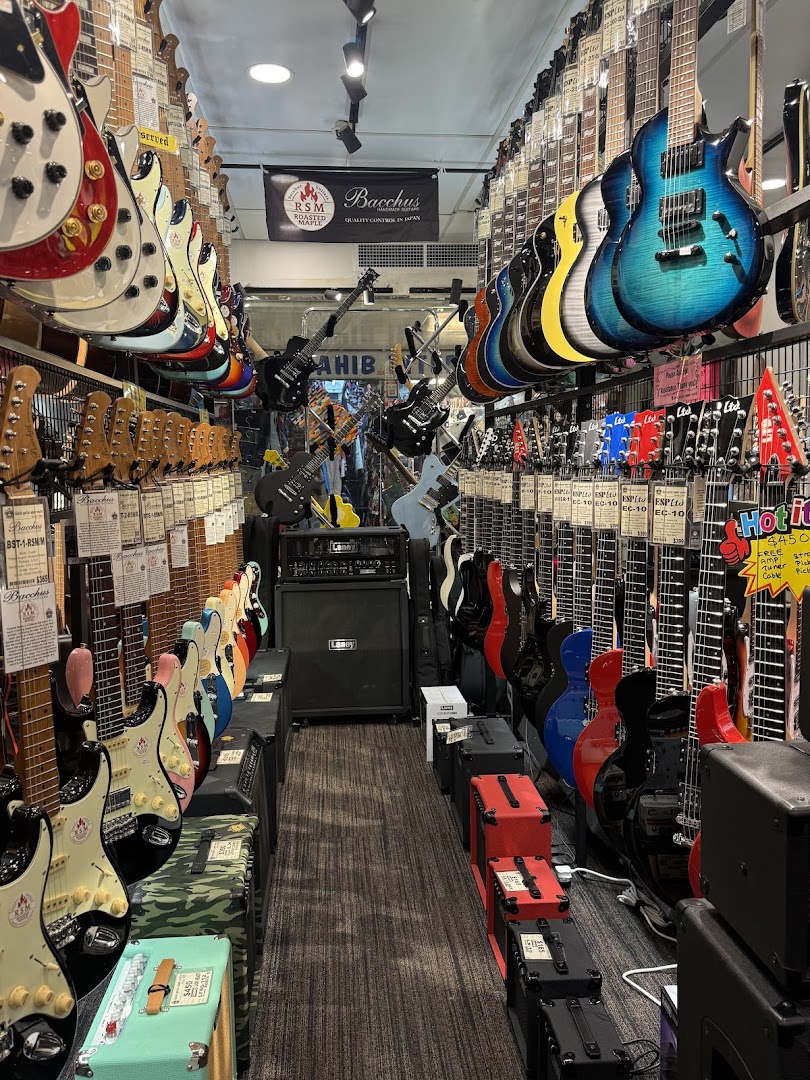 A narrow aisle in a music store showcasing a vast collection of guitars and amplifiers.