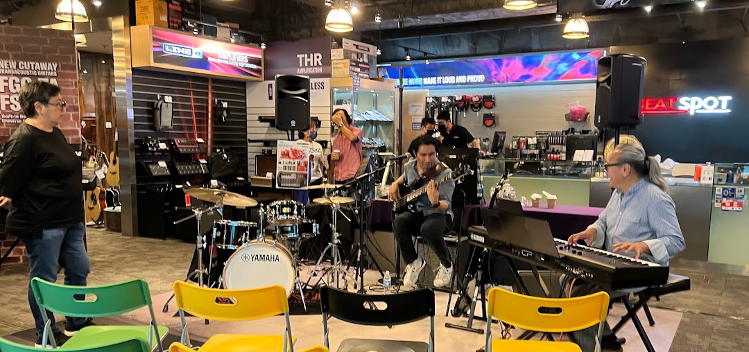 A live band performs inside the Yamaha Music Store, surrounded by musical instruments and equipment.