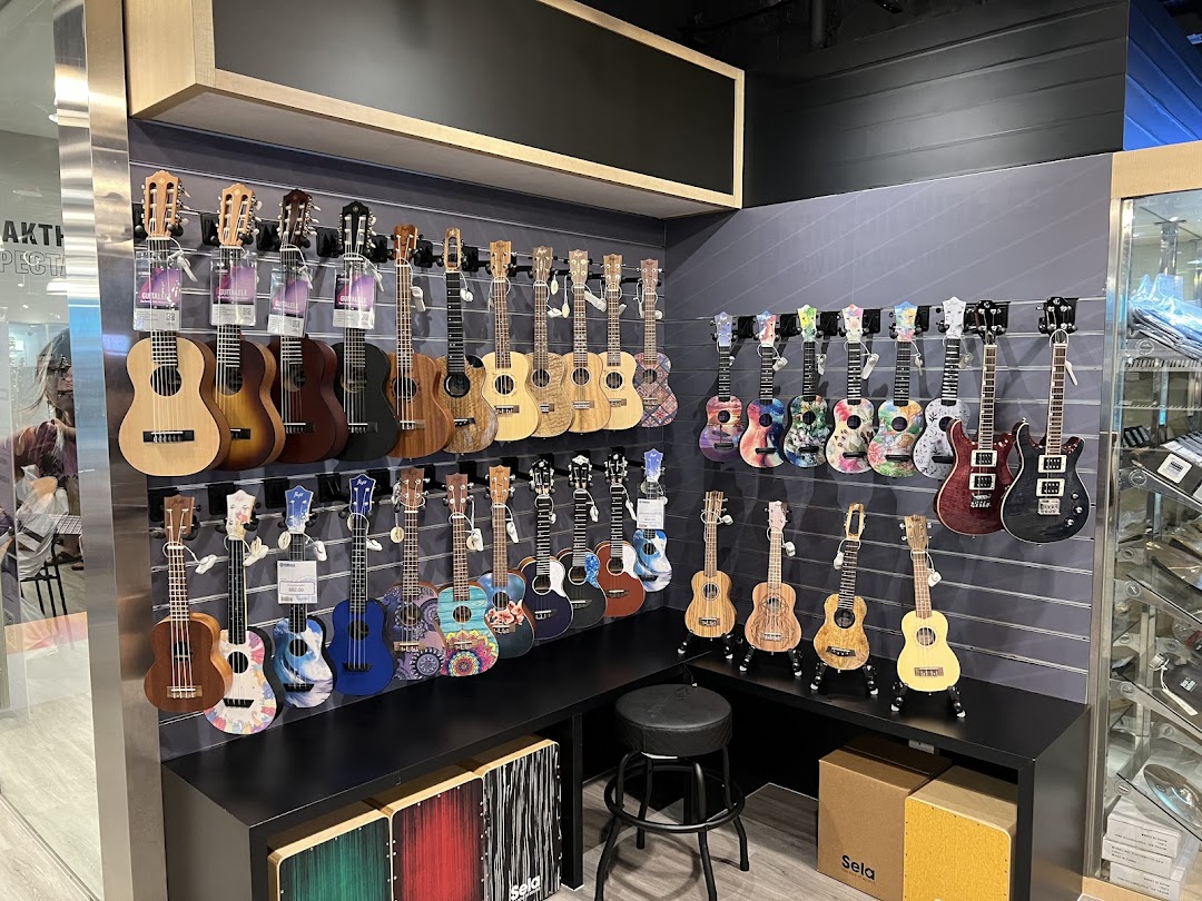 A vibrant display of various ukuleles and guitars on a wall in a music store.