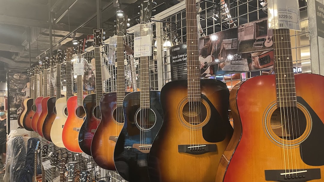 A vibrant display of acoustic guitars in various colors lines the wall of a music store.