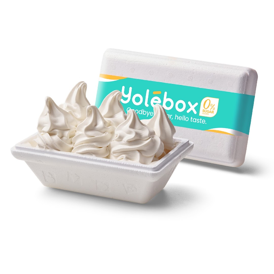 A Yolebox container filled with creamy soft-serve frozen yogurt, with the Yolebox packaging behind it.