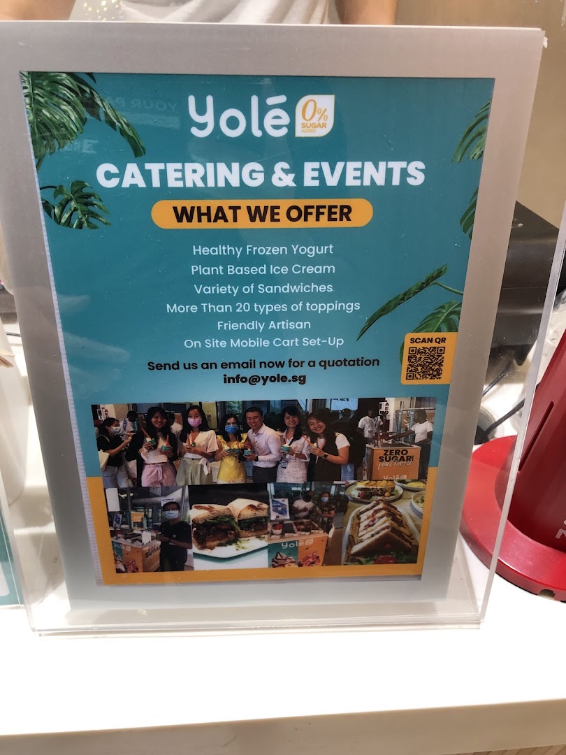 A Yolé sign promoting catering and events services, listing offerings like frozen yogurt and sandwiches.