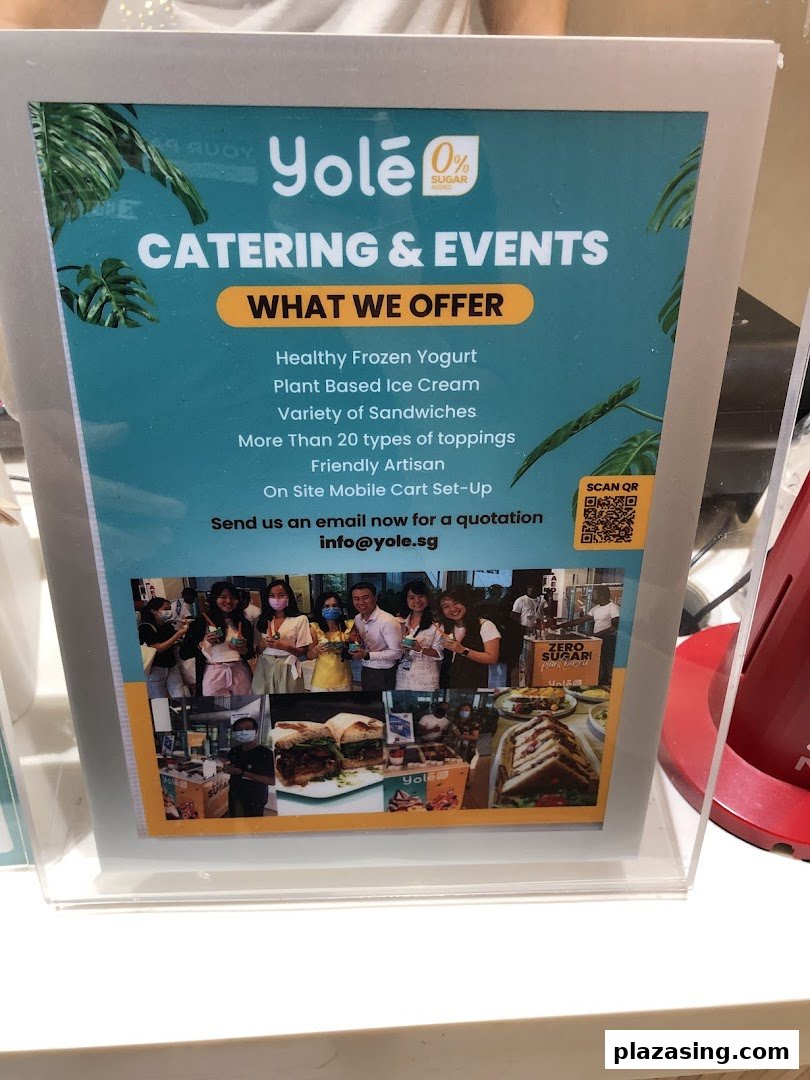 A Yolé sign promoting catering and events services, listing offerings like frozen yogurt and sandwiches.