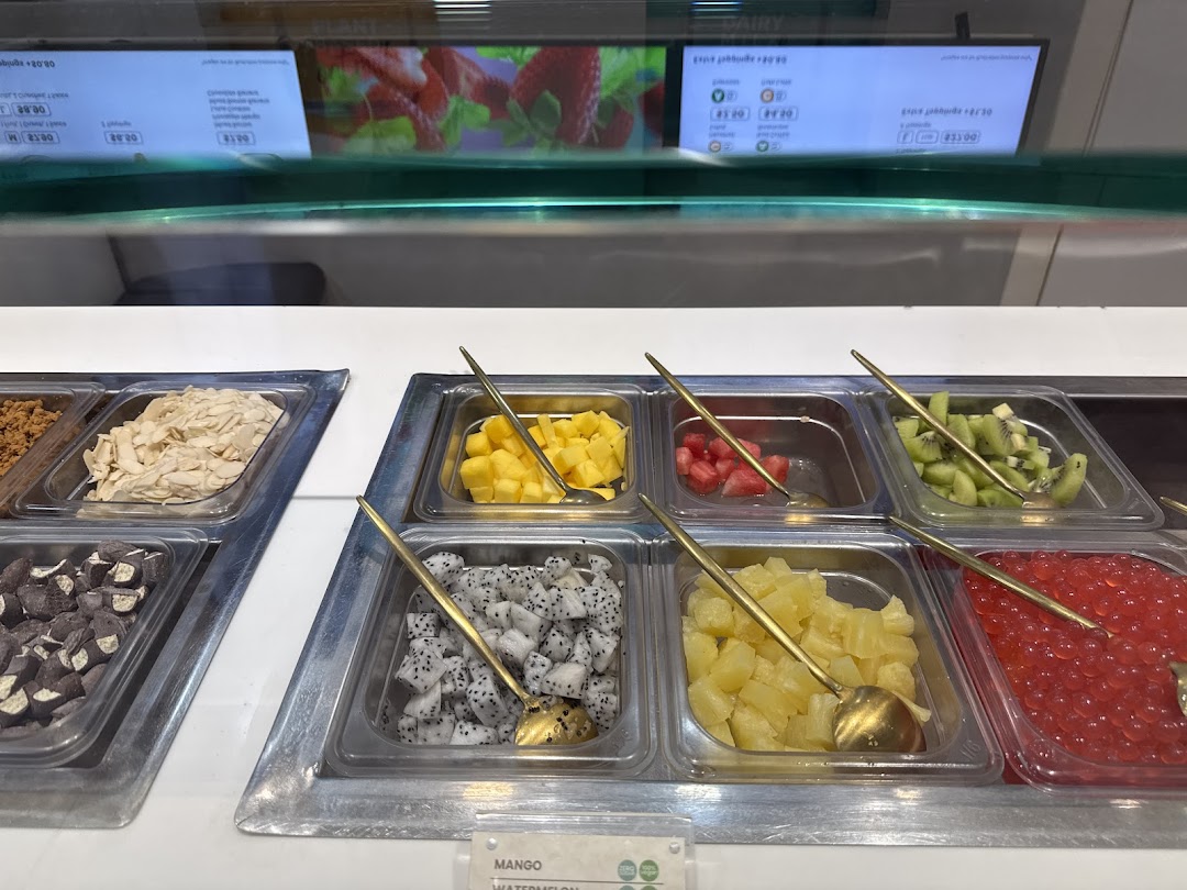 A vibrant display of fresh fruit and toppings for frozen yogurt at Yolé, with a digital menu screen.
