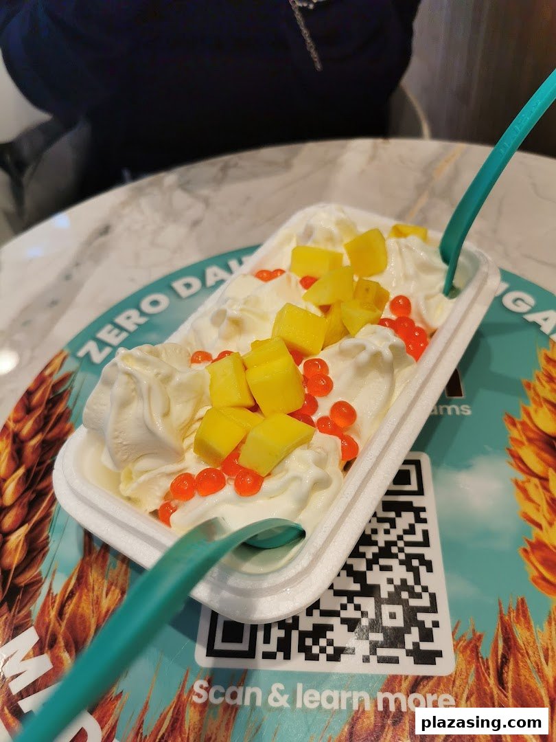 A delightful frozen yogurt dessert with mango and popping pearls, served on a branded placemat.