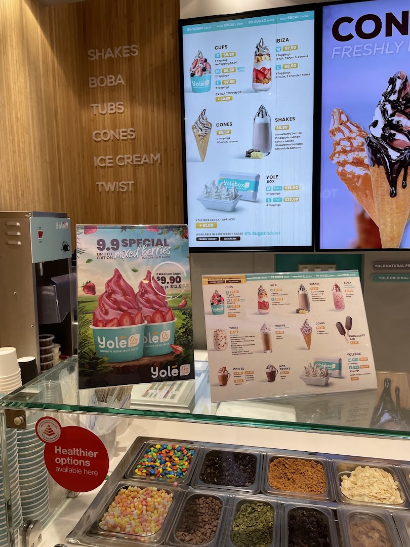 Yolé frozen yogurt shop interior featuring a toppings bar, digital menus, and promotional displays.