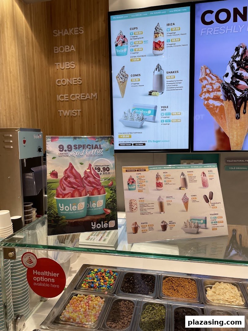 Yolé frozen yogurt shop interior featuring a toppings bar, digital menus, and promotional displays.