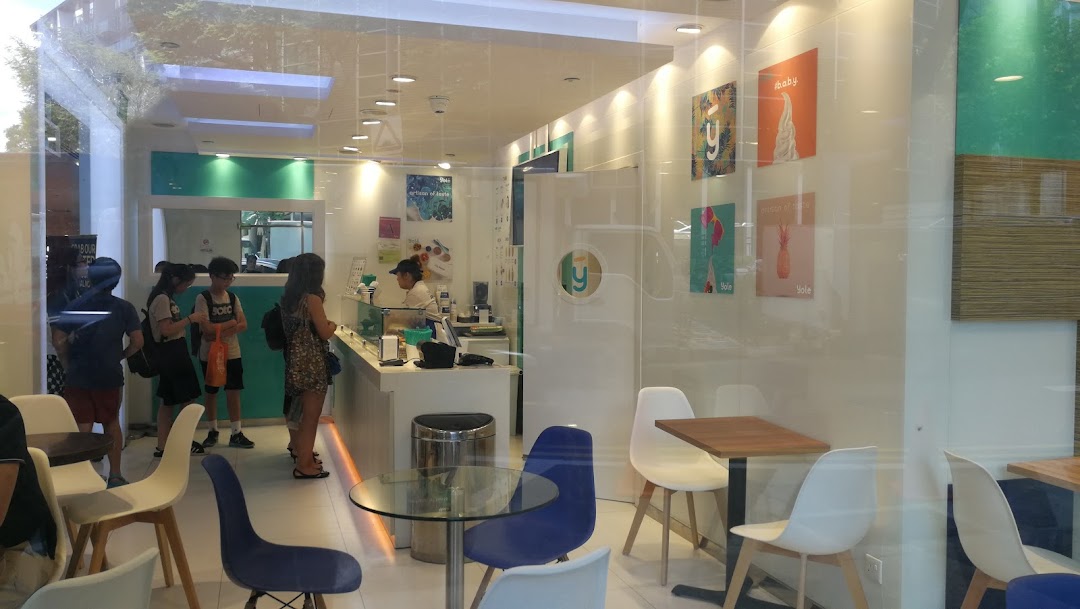 Inside Yolé Plaza Singapura, customers queue at the counter of the bright, modern frozen yogurt shop with seating.
