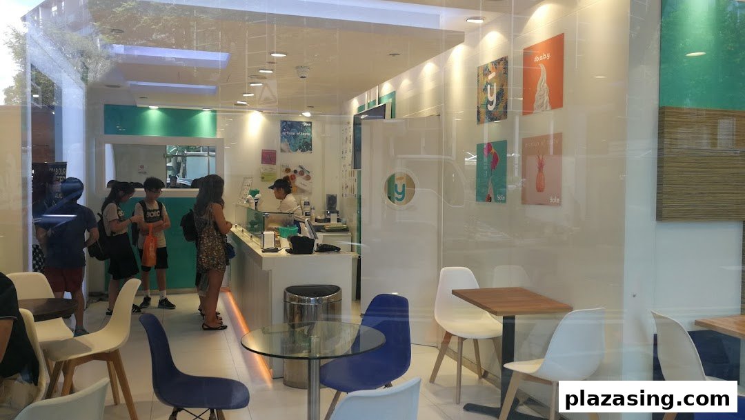 Inside Yolé Plaza Singapura, customers queue at the counter of the bright, modern frozen yogurt shop with seating.