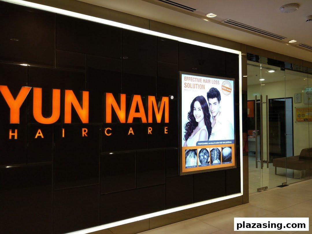 The image displays the illuminated Yun Nam Hair Care shopfront with a promotional poster and glass entrance.