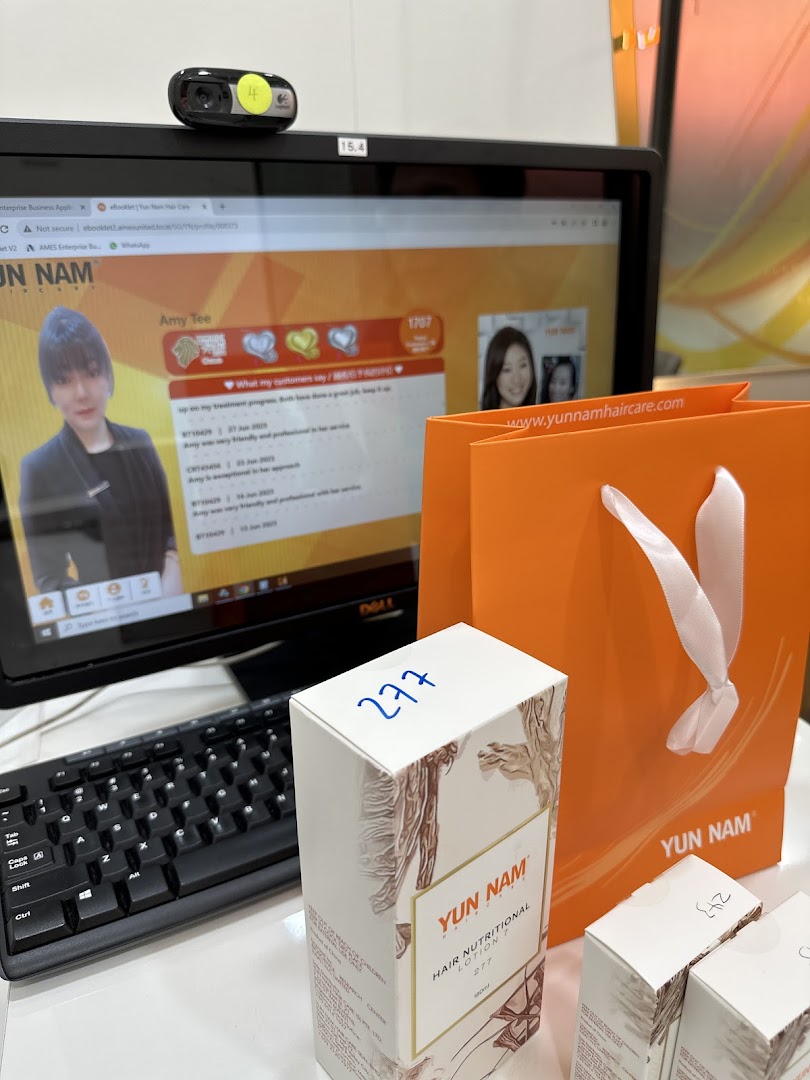 A computer screen displaying customer reviews, a Yun Nam Hair Care product box, and an orange shopping bag.