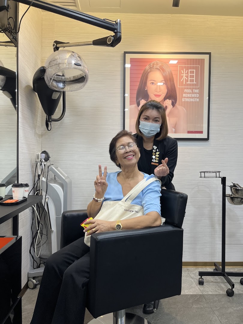 A happy customer and staff member pose in a Yun Nam Hair Care treatment room.