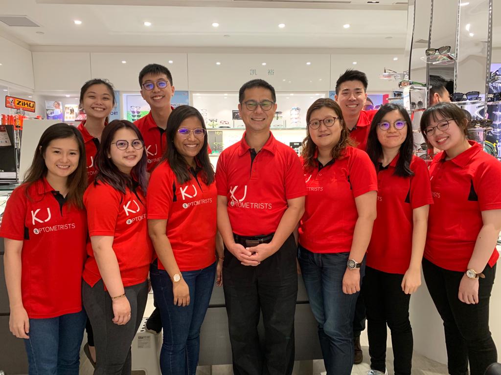 A team of friendly optometrists in red shirts smiling inside the ZEISS VISION CENTER by KJ Optometrists.