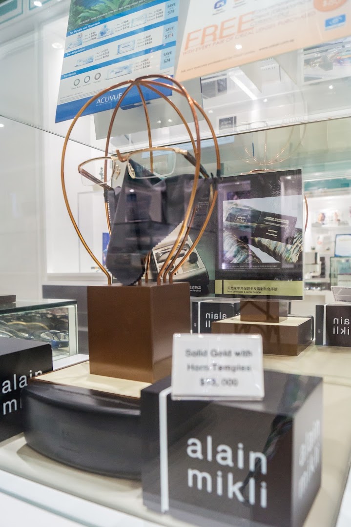 Close-up of a display case inside an optical shop, featuring eyeglasses, contact lenses, and product information.