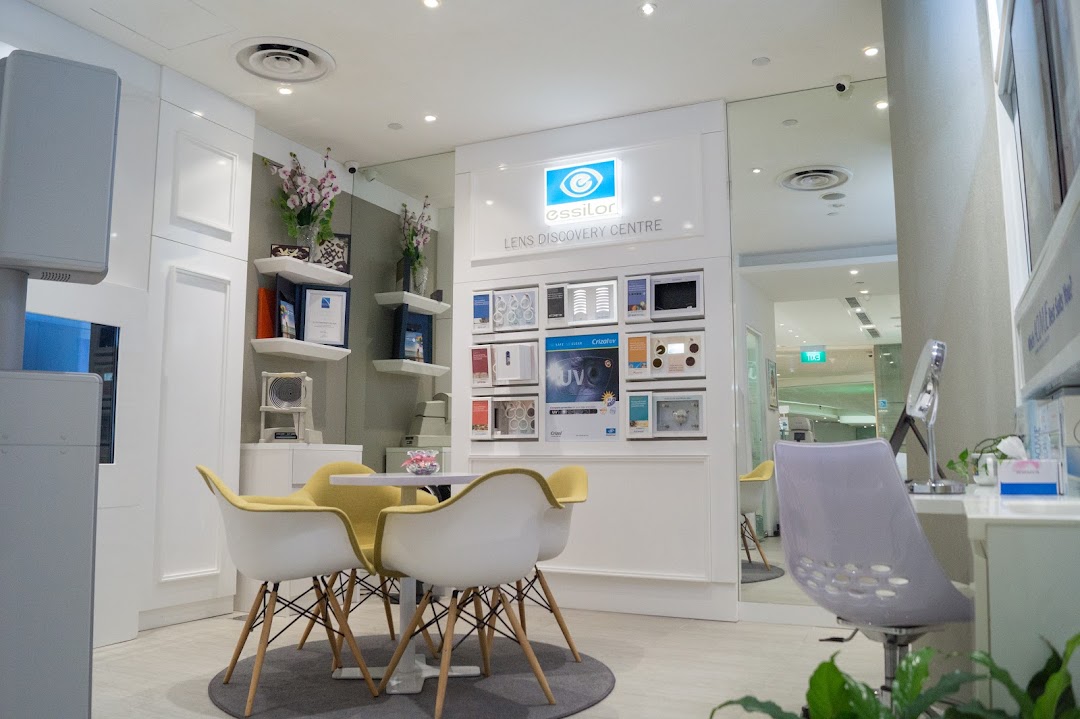 A bright, modern interior of an optometrist shop featuring a lens display and comfortable seating.
