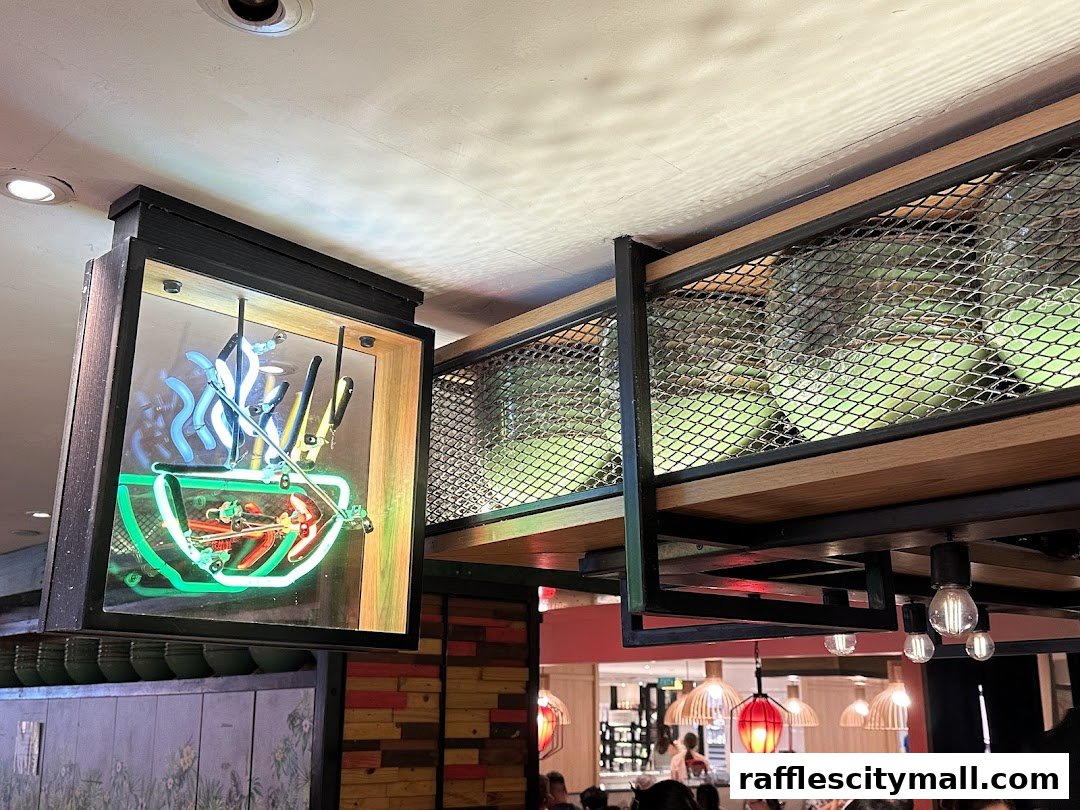 A neon sign depicting a bowl of noodles hangs in a restaurant with modern decor.