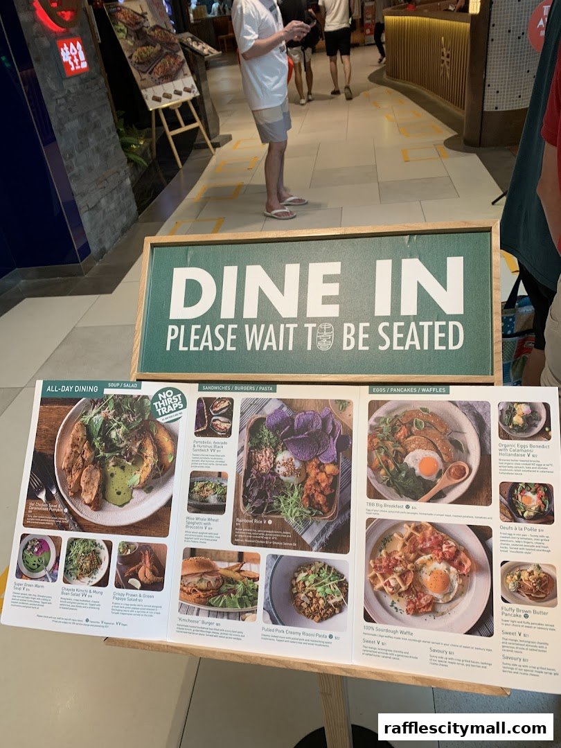 A menu board displays various dishes from Tiong Bahru Bakery, with a 'Dine In' sign above.