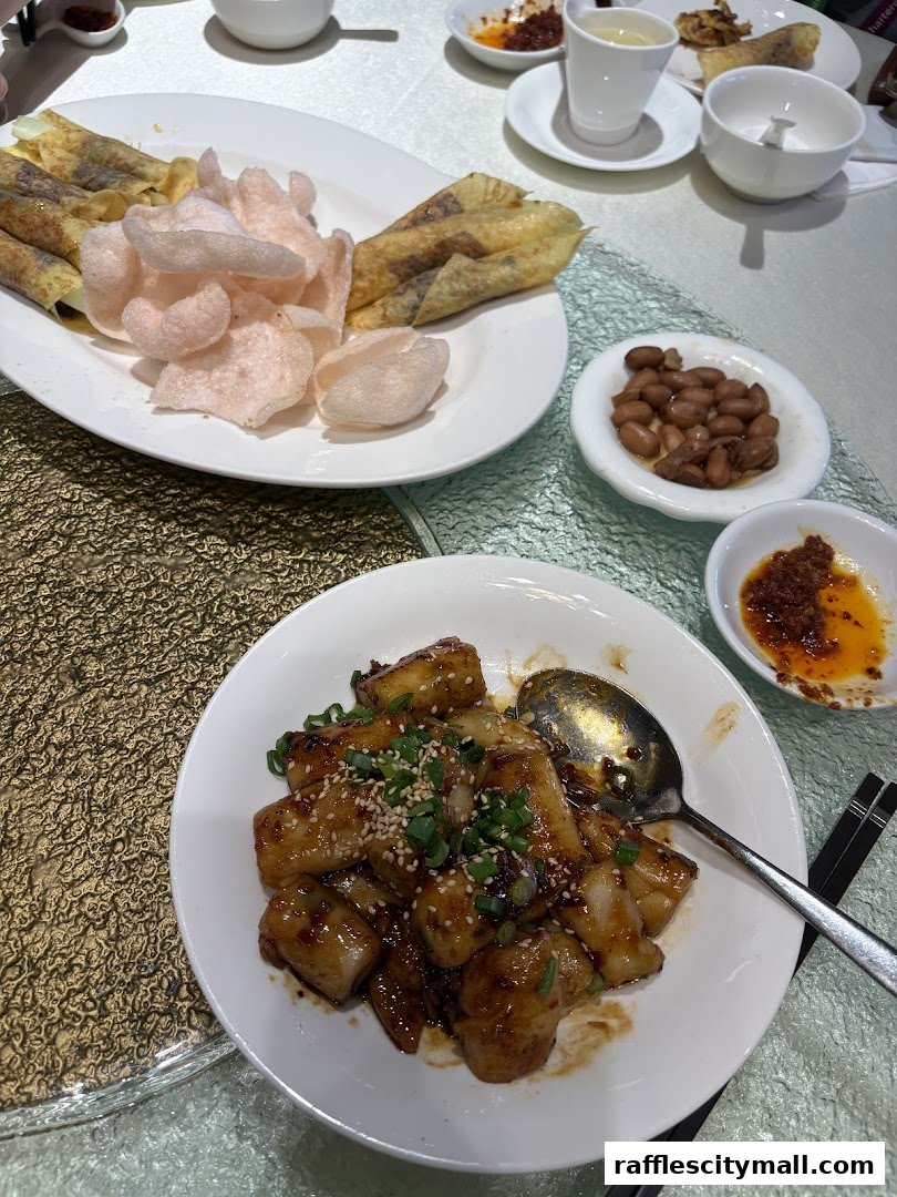 A table laden with delicious Asian dishes, including spring rolls, rice cakes, and peanuts.