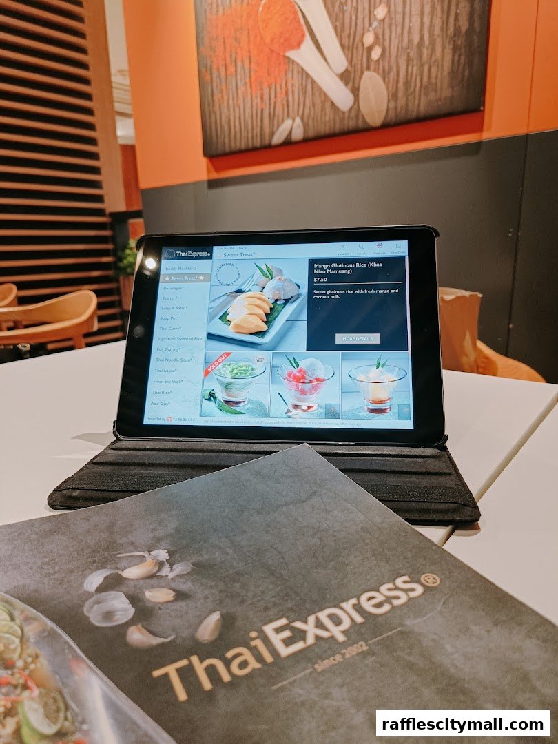 A tablet displaying a Thai Express menu next to a physical menu on a table.