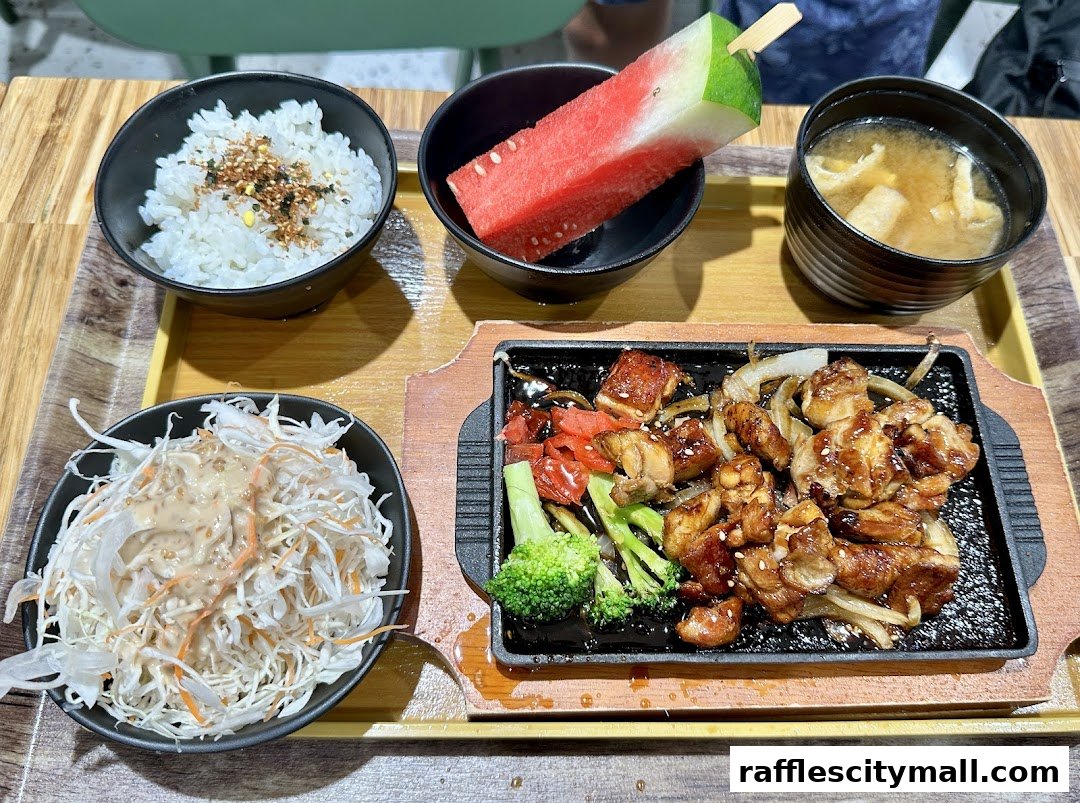 A delicious meal featuring teriyaki chicken, rice, salad, miso soup, and watermelon.