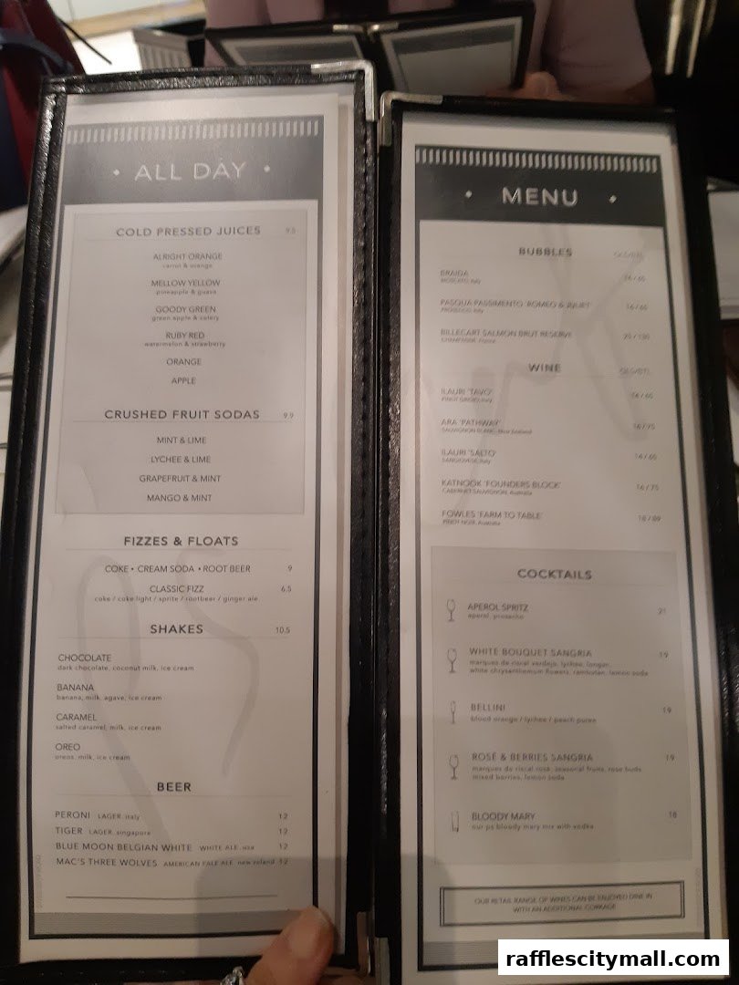 A menu from PS.Cafe Raffles City, featuring juices, sodas, shakes, beers, wines, and cocktails.