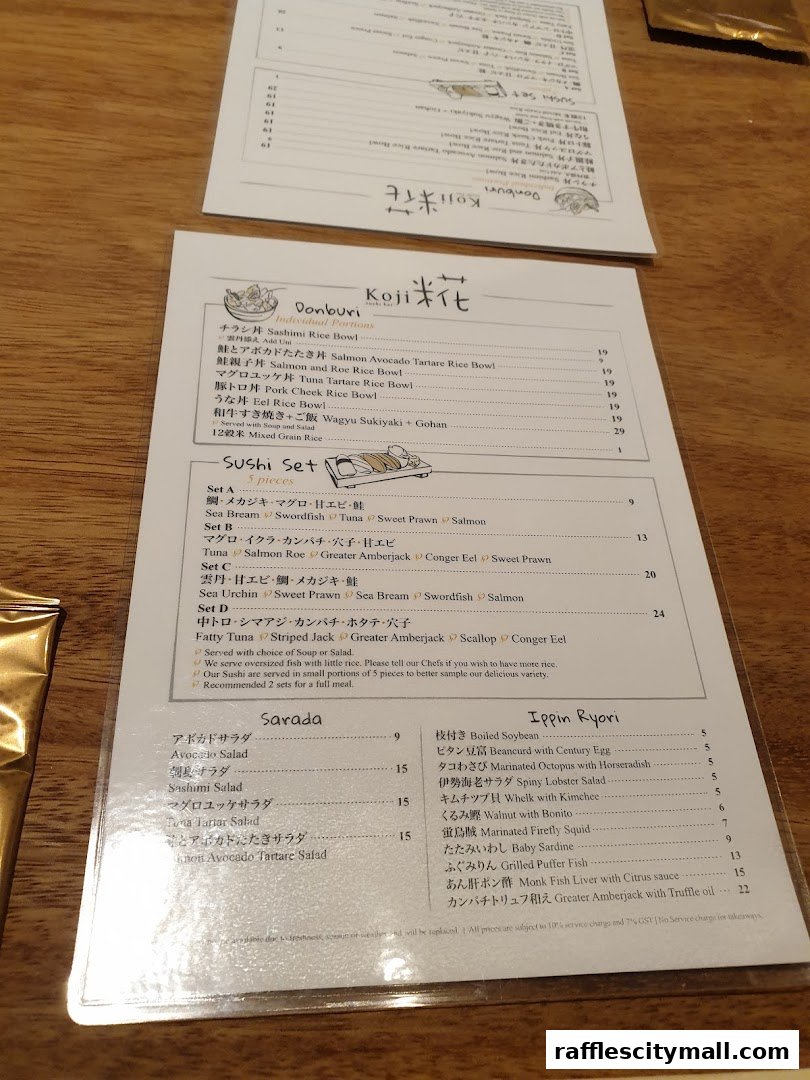 A menu from Koji Sushi Bar featuring Donburi, Sushi Sets, Sarada, and Ippin Ryori.