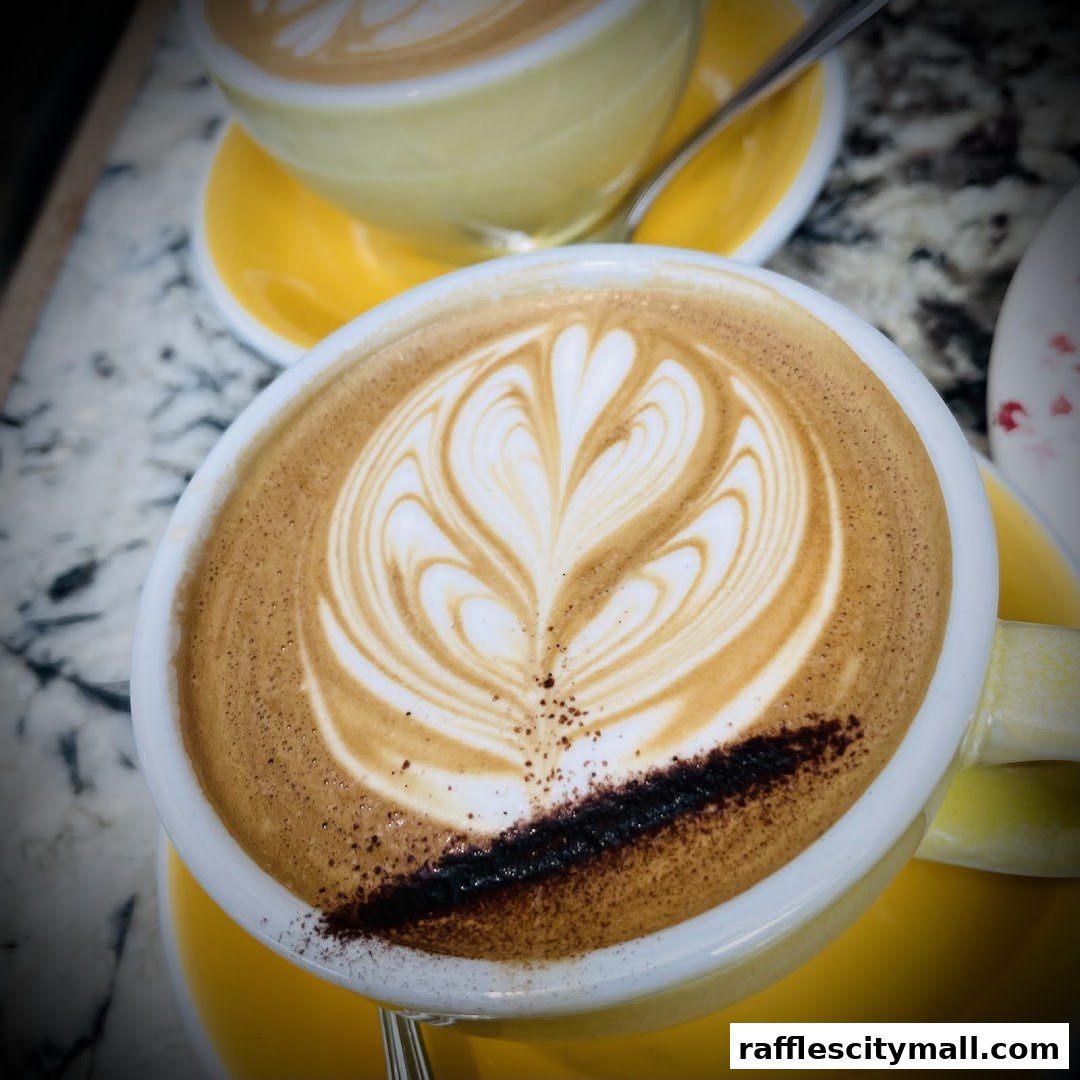 A close-up of a latte with intricate latte art in a yellow cup.