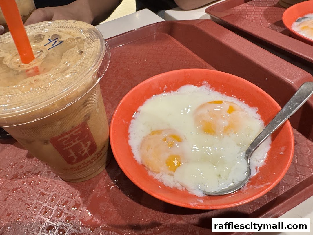 A close-up of a Ya Kun Kaya Toast iced coffee and soft-boiled eggs on a tray.