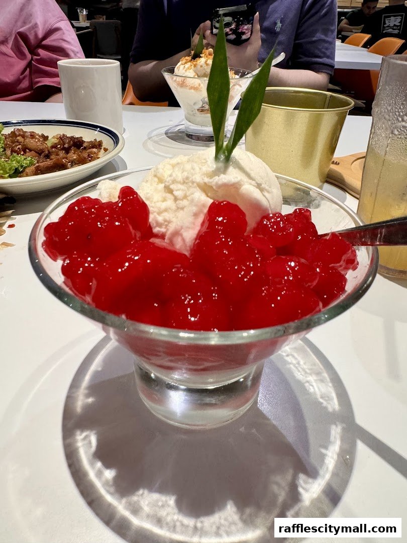 A close-up of a dessert with ice cream and red jelly, served in a glass bowl.