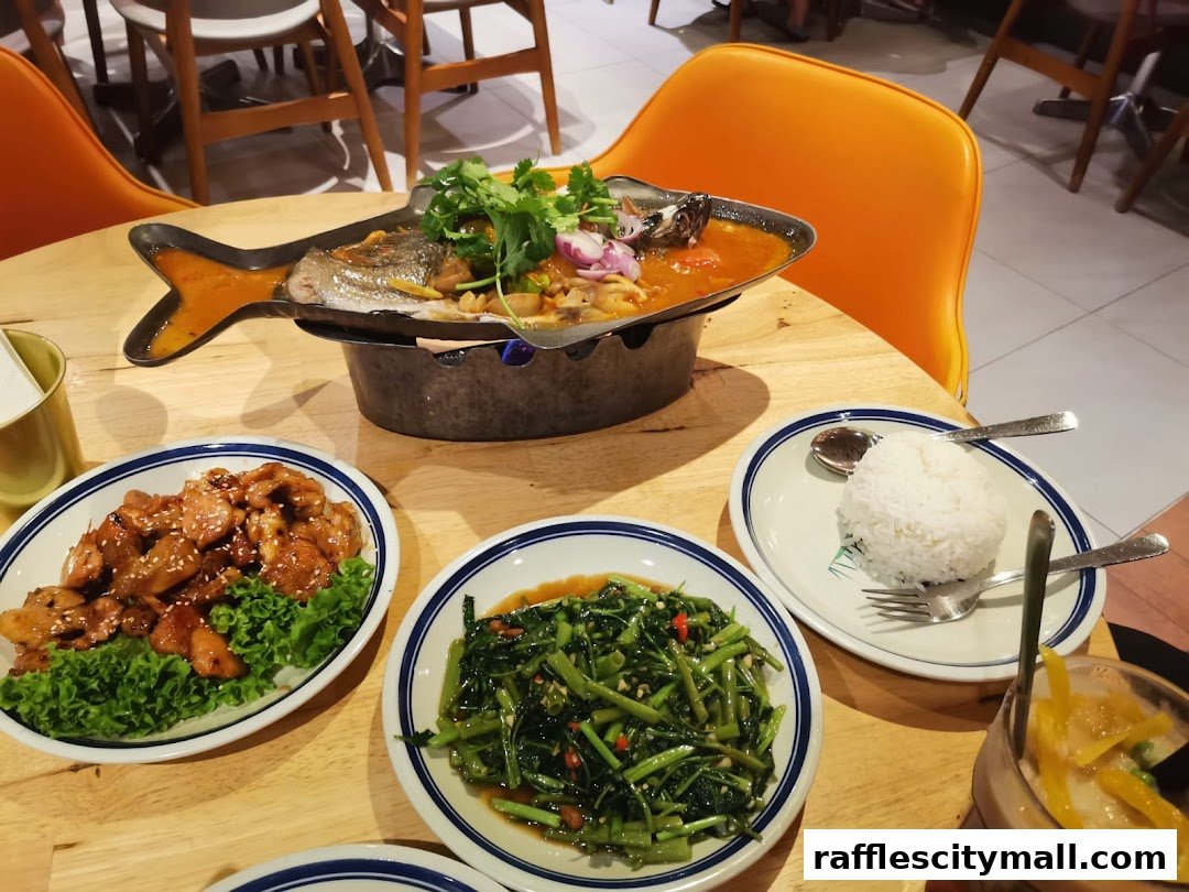 A table laden with Thai dishes, including a whole fish, stir-fried vegetables, and rice.