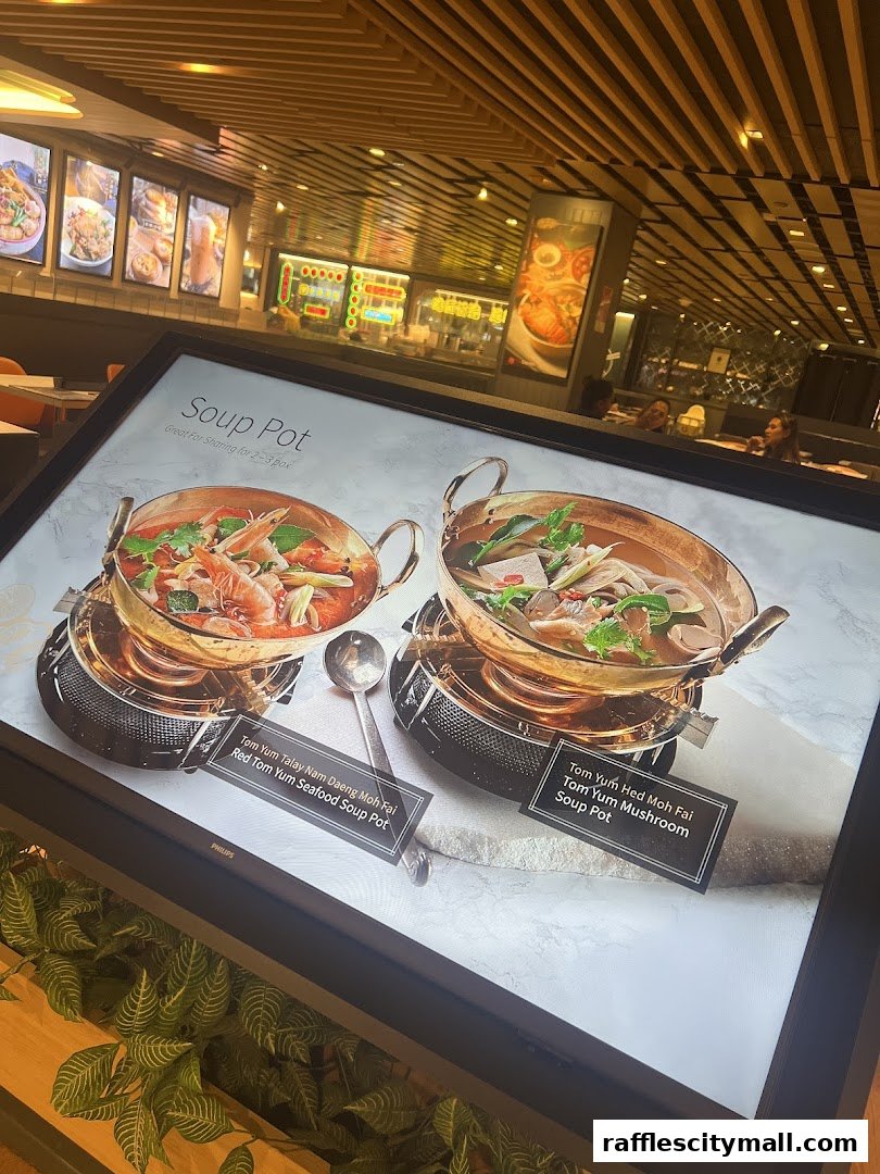 A close-up of a digital menu displaying two steaming Thai soup pots.