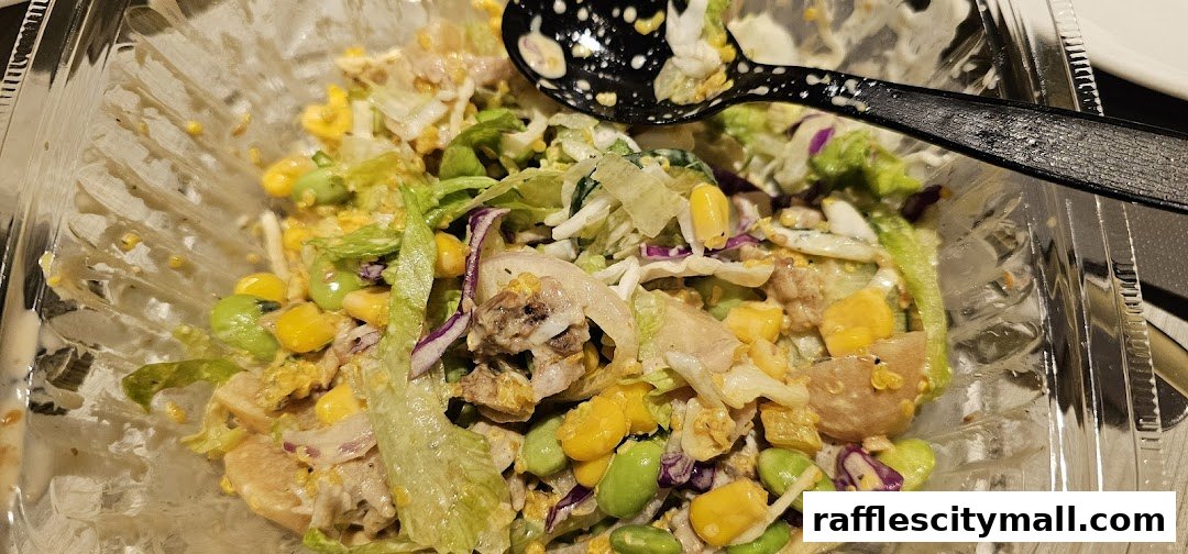 A close-up of a delicious salad in a clear plastic container with a spoon.
