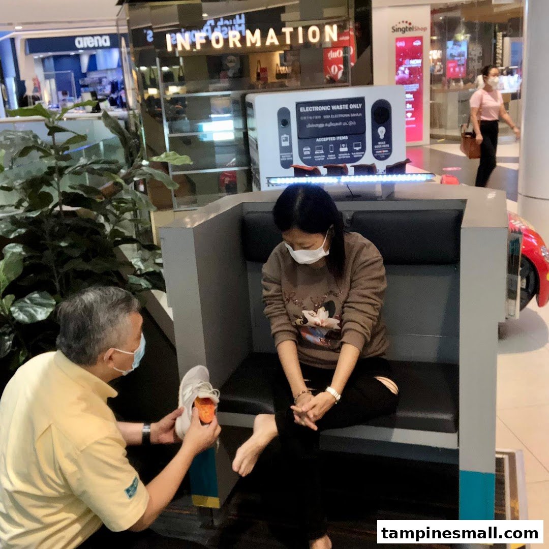 A staff member assists a customer with an orthotic fitting in a mall setting.