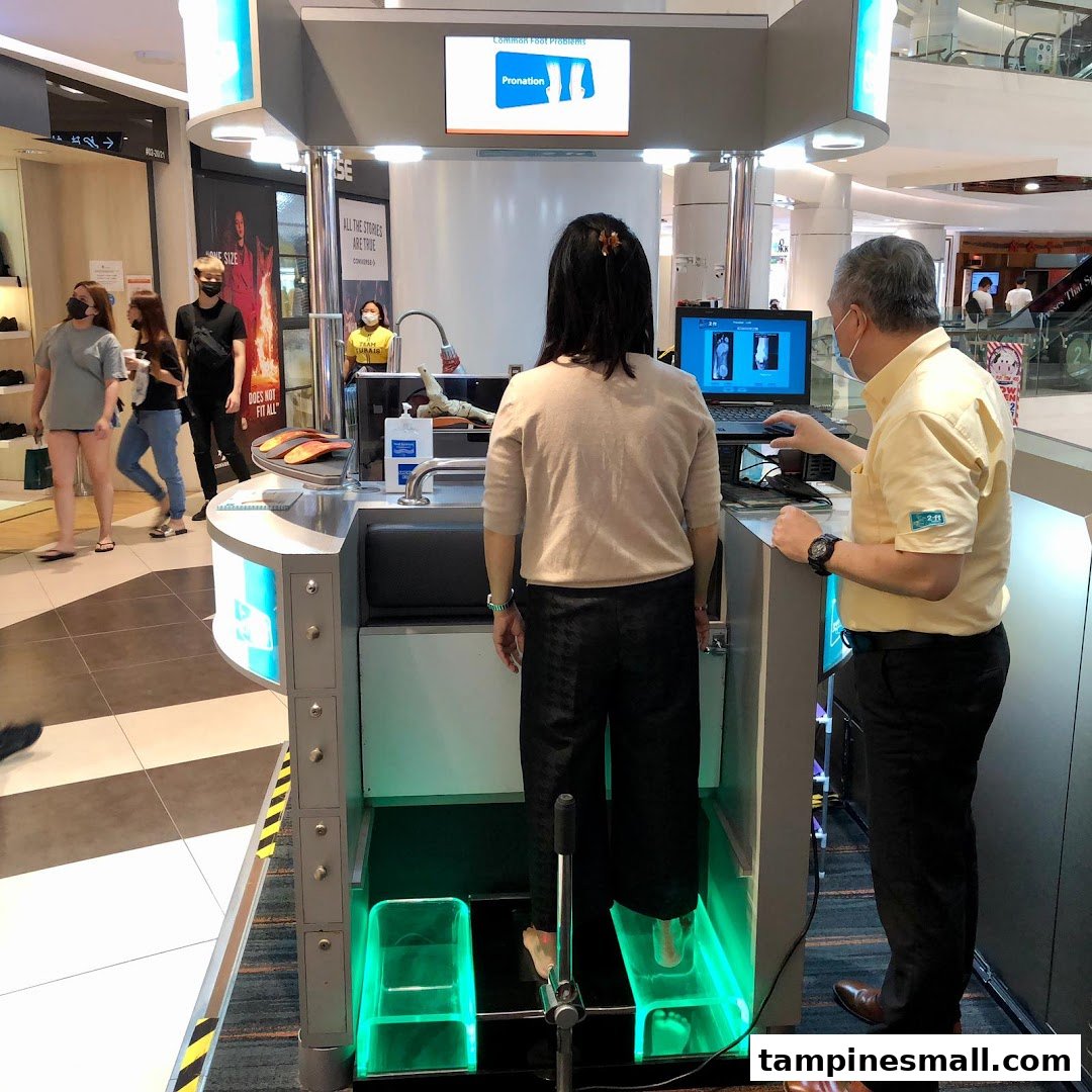 A customer receives a foot scan at a 2ft Orthotics station, assisted by a staff member.