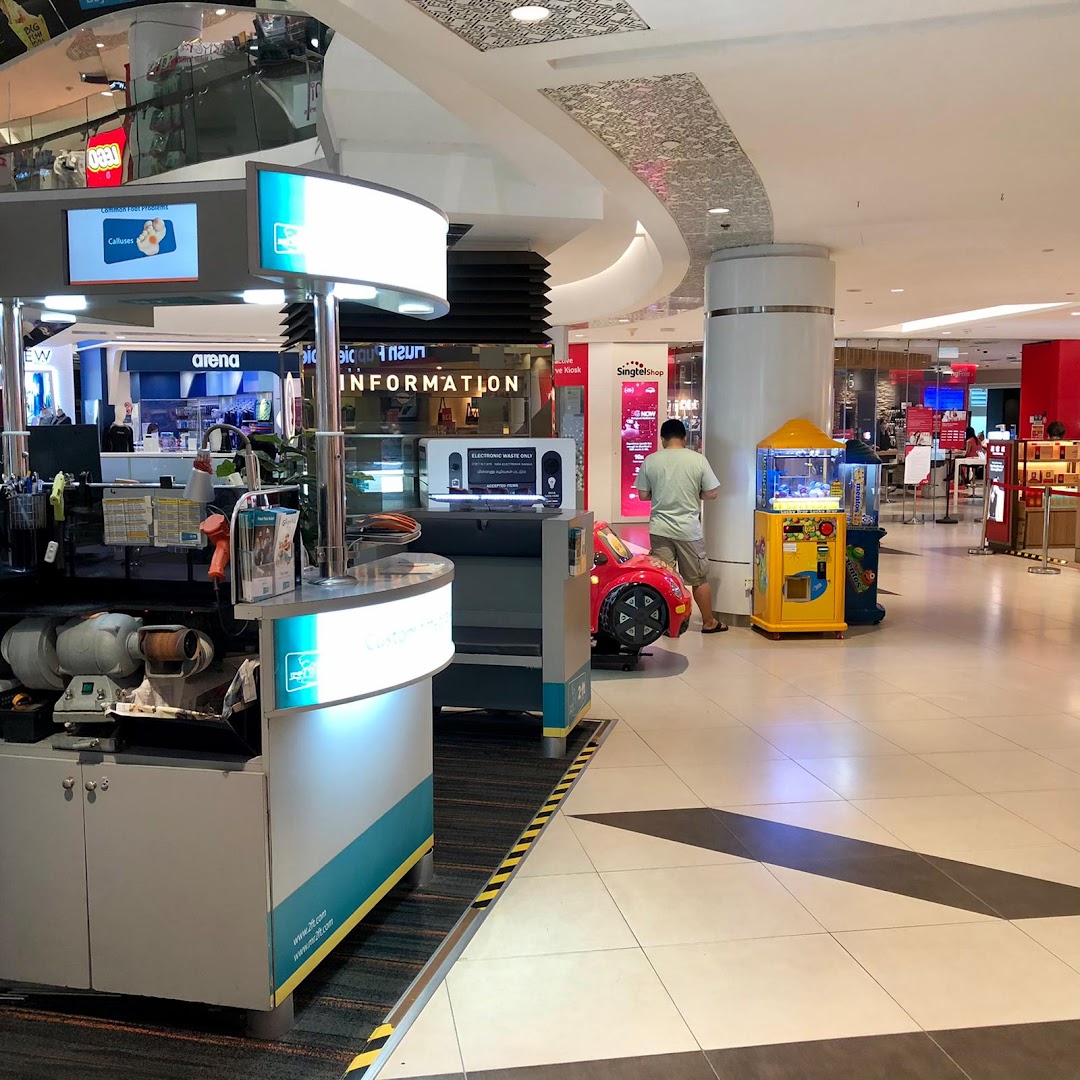 An interior view of a shopping mall featuring the 2ft Orthotics kiosk, a man, and arcade machines.